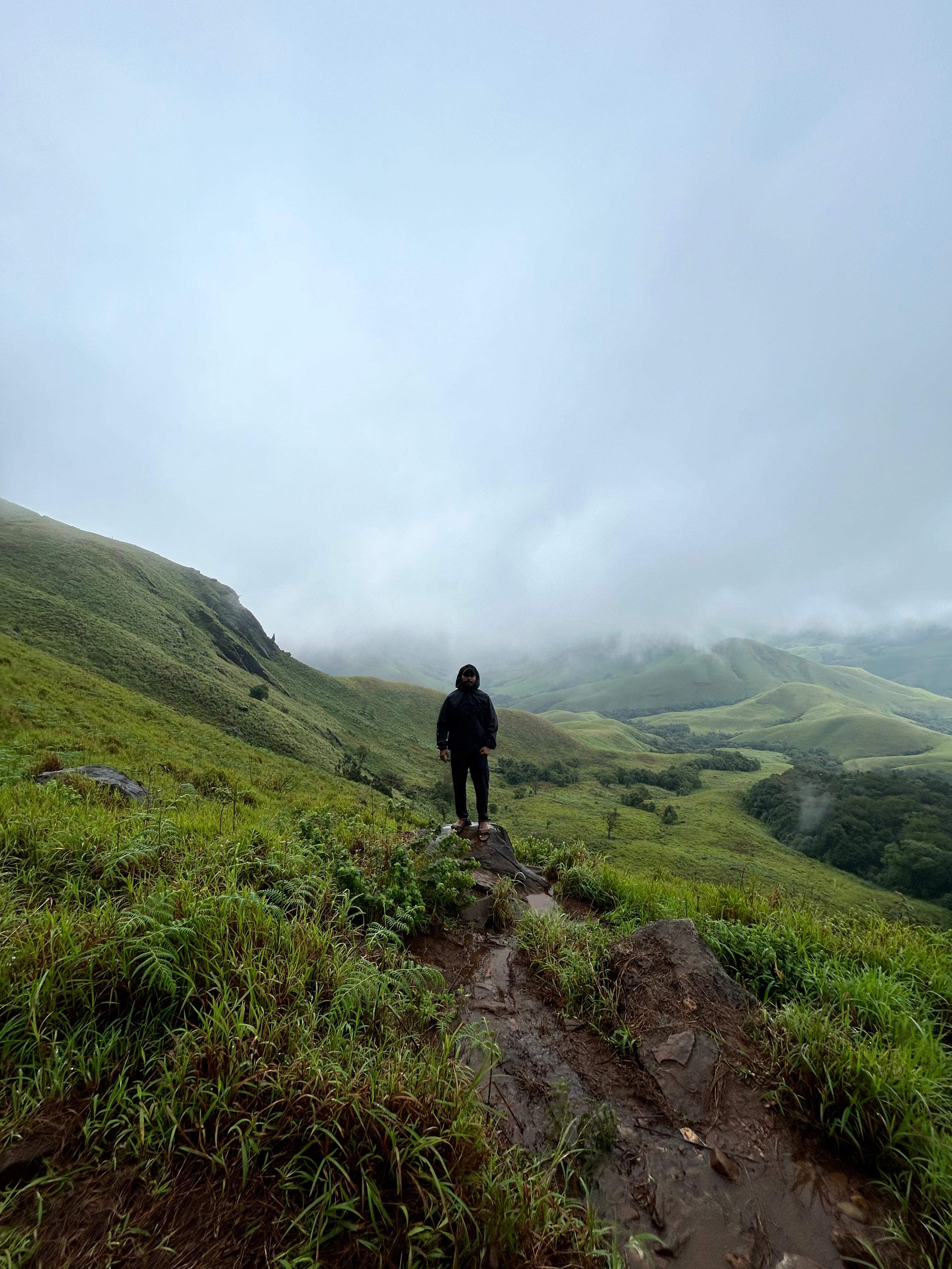 Trekker hiking through lush green grasslands on the Kudremukh Trek
